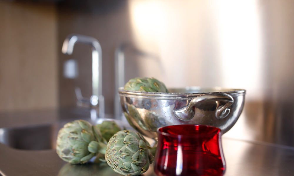 decoración cocina Cuenco de latón con alcachofas y vaso rojo para decorar la cocina.
